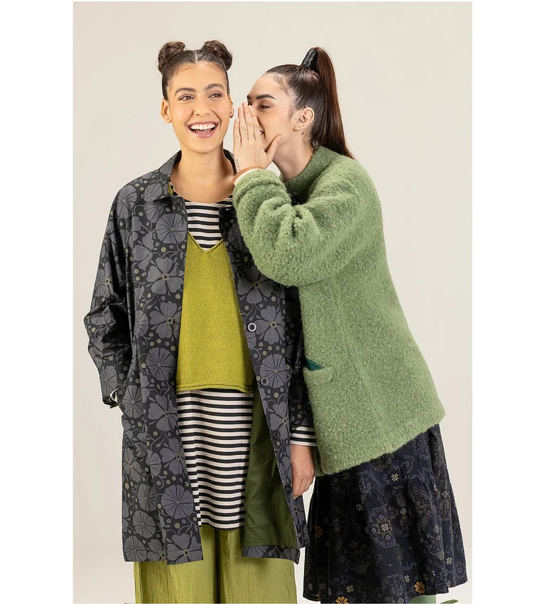 Two women wearing outerwear from Gudrun Sjödén. One is wearing a green bouclé jacket in wool and the other is wearing a gray patterned coat. 