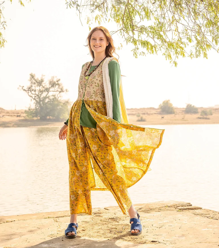 A woman wearing a yellow floral dress and yellow floral trousers from Gudrun Sjödén.