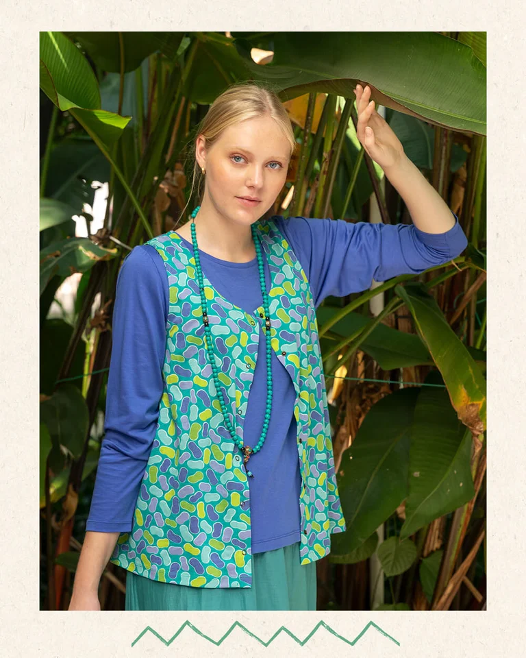 A woman wearing a blue sweater and patterned vest from Gudrun Sjödén.  