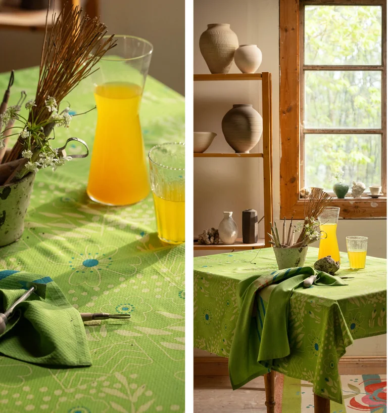 A close-up of a pea green, patterned tablecloth and a matching tea towel from Gudrun Sjödén.