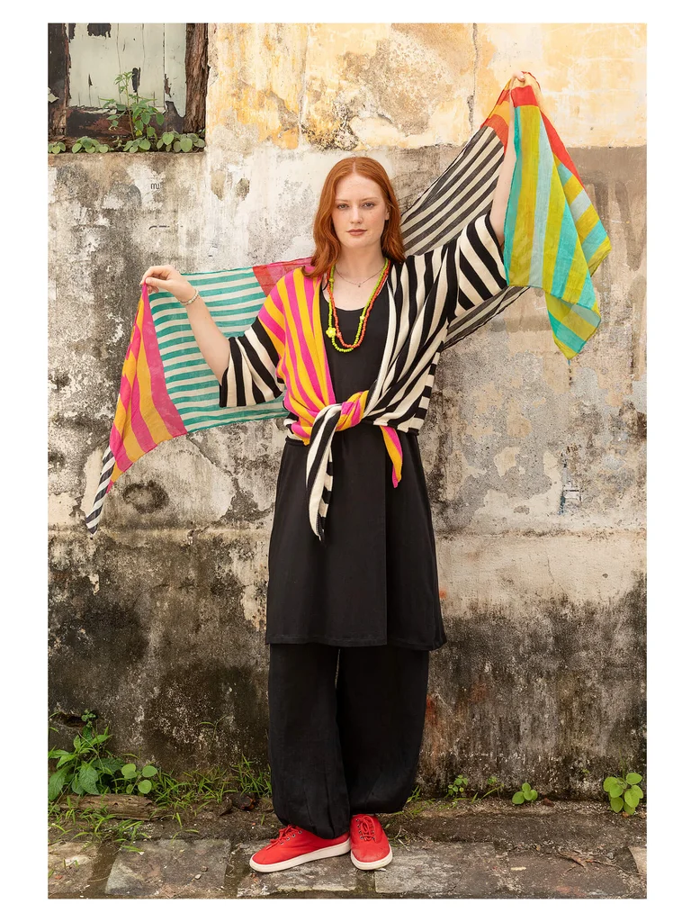 A woman wearing a striped wrap cardigan and matching striped shawl from Gudrun Sjödén. 