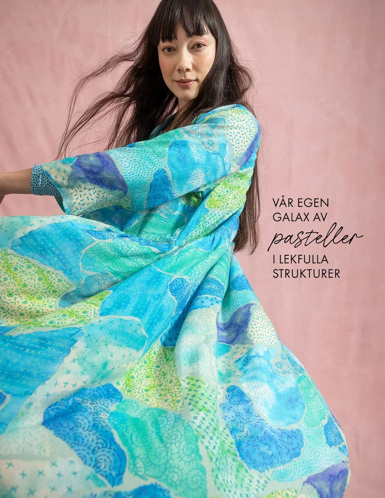 En kvinna klädd i en mönstrad blå klänning från Gudrun Sjödén. 