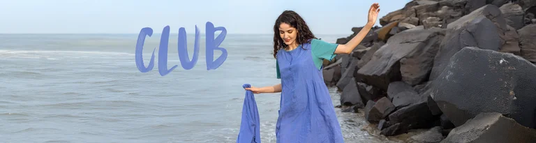 A woman wearing a blue, woven sleeveless dress in linen from Gudrun Sjödén.