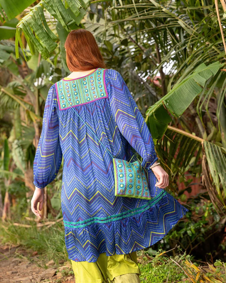 A woman with her back to the camera wearing blue-green clothing from Gudrun Sjödén. 