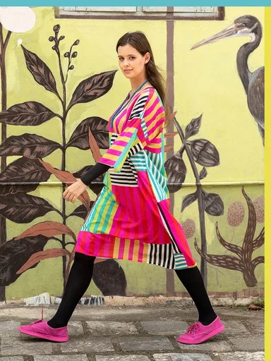 A woman photographed while walking, wearing a striped dress from Gudrun Sjödén.
