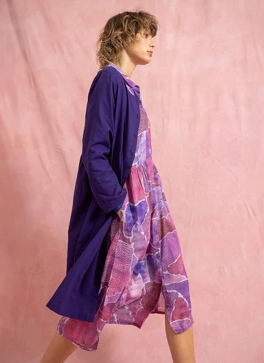 En kvinna klädd i en mönstrad lila klänning från Gudrun Sjödén. 