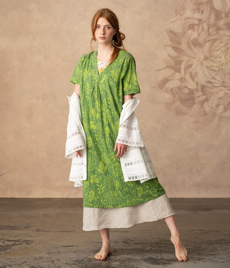 A woman wearing a patterned green dress from Gudrun Sjödén.   