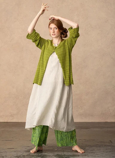 A woman wearing a white dress and green cardigan from Gudrun Sjödén.  