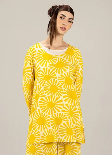 A woman wearing matching yellow, patterned clothing from Gudrun Sjödén. 