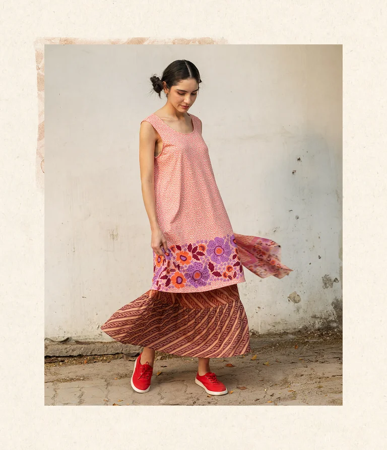 A woman wearing a pink dress with a floral pattern from Gudrun Sjödén. 