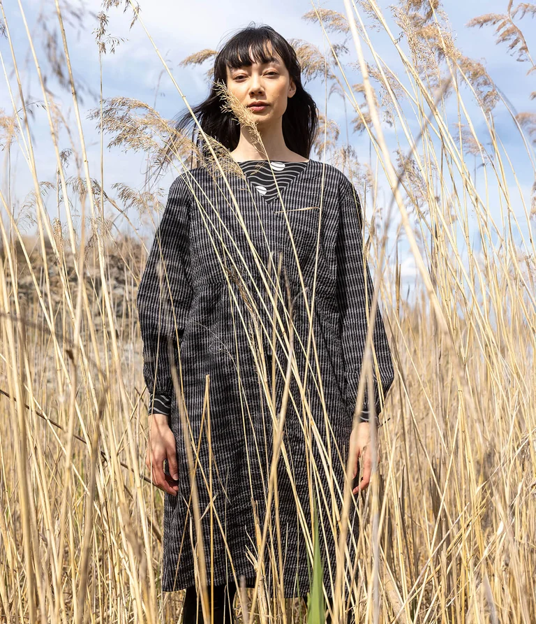A woman wearing a black patterned dress from Gudrun Sjödén. 
