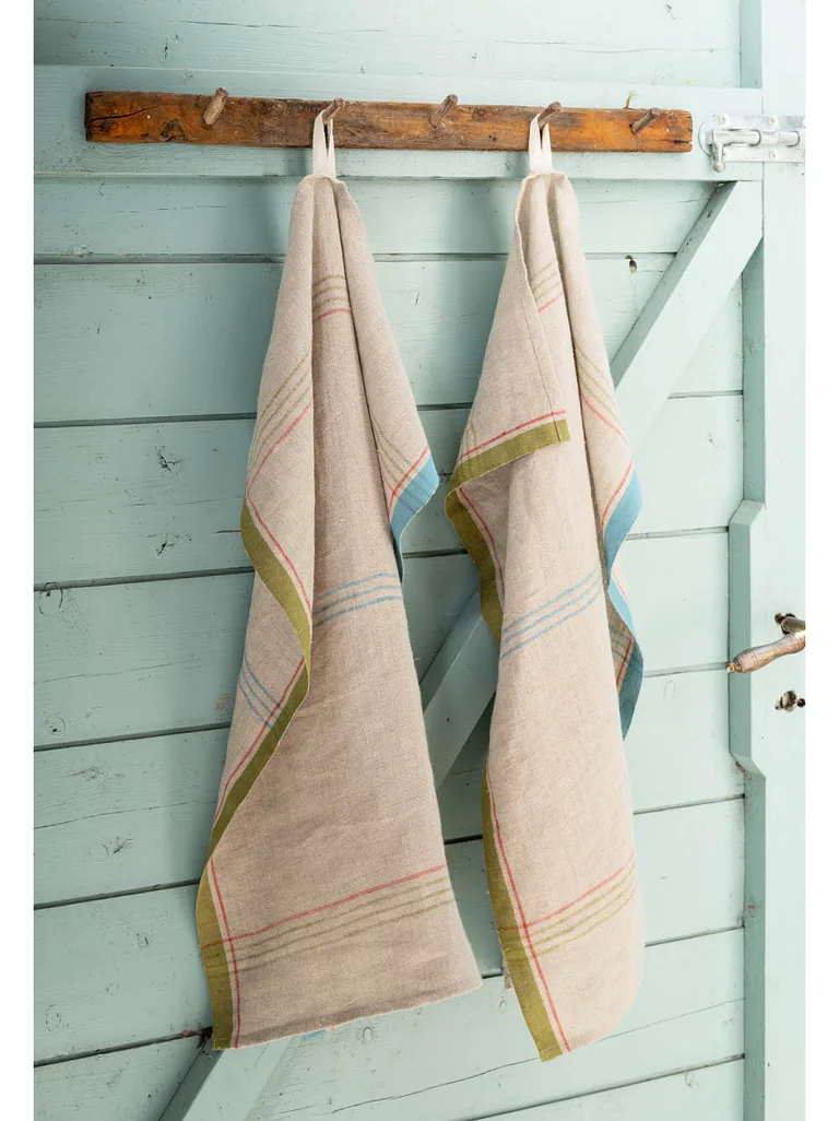 Striped kitchen towels in a linen blend from Gudrun Sjödén on a light blue door.