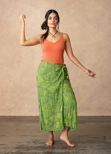 A woman in an orange tank top and green skirt from Gudrun Sjödén.  