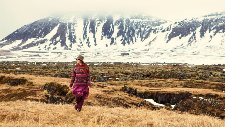 An image of a woman in an open field wearing colorful clothing from Gudrun Sjödén. 