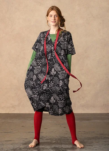 A woman wearing a black patterned dress from Gudrun Sjödén. 