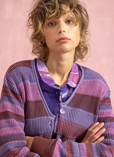 En kvinna klädd i en randig stickad kofta från Gudrun Sjödén. 