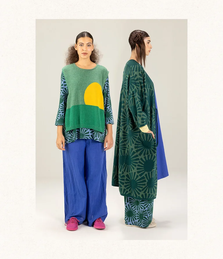 Two women standing beside one another, wearing layers of clothing from Gudrun Sjödén.  