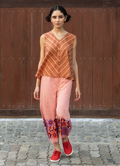 A woman wearing a patterned blouse and pants from Gudrun Sjödén.  
